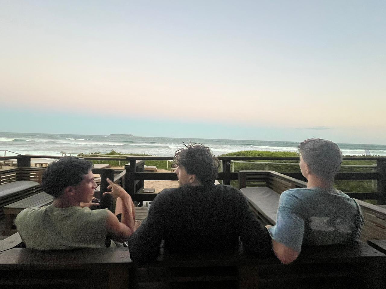 Gabriel conversando com amigos vendo o pôr do sol na praia